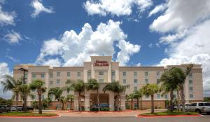 un grand bâtiment avec des palmiers devant lui dans l'établissement Hampton Inn & Suites McAllen, à McAllen