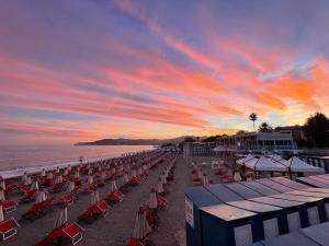 a beach with chairs and umbrellas at sunset at Due passi dal mare in Savona