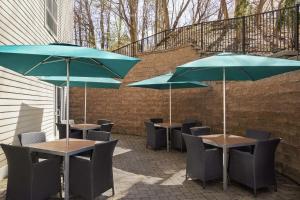 2 tafels en stoelen met parasols op een patio bij Hampton Inn & Suites Exeter in Exeter