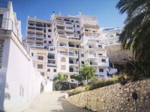 a large white apartment building with a stone wall at Apartamentos Bon Amb in Faro de Cullera