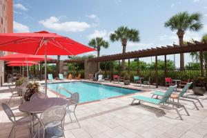 a pool with tables and chairs and a red umbrella at Home2 Suites by Hilton Florida City in Florida City