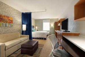 Home2 Suites by Hilton Florida City في مدينة فلوريدا: غرفة في الفندق مع أريكة وسرير