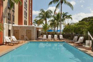 マイアミにあるHampton Inn Miami-Airport Westのヤシの木が茂るスイミングプール(ラウンジチェア付)