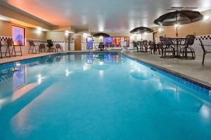 a large swimming pool in a hotel with tables and chairs at Hampton Inn Mitchell in Mitchell