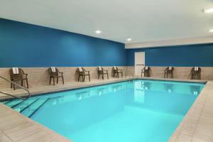 a swimming pool in a hotel room with chairs at Hampton Inn Kansas City Blue Springs in Blue Springs