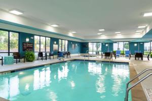 a pool in a hotel with tables and chairs at Hampton Inn & Suites Marshalltown in Marshalltown