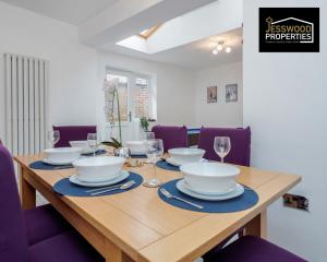 a wooden table with bowls and plates and wine glasses at 6 Bedroom Contractor House at Jesswood Properties Short Lets With Parking,Wifi & Pool Table in Luton
