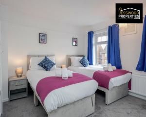 2 łóżka w pokoju z niebieskimi zasłonami w obiekcie 6 Bedroom Contractor House at Jesswood Properties Short Lets With Parking,Wifi & Pool Table w Luton