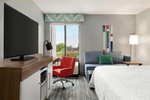 a hotel room with a bed and a flat screen tv at Hampton Inn Kansas City Blue Springs in Blue Springs