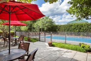 a patio with a table with a red umbrella and a pool at Hampton Inn Middletown in Middletown