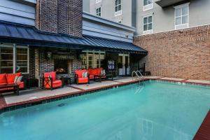 a swimming pool with red chairs and a fireplace at Hampton Inn & Suites Mobile - Downtown Historic District in Mobile