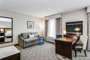 ein Hotelzimmer mit einem Schreibtisch, einem Sofa und einem TV in der Unterkunft Hampton Inn & Suites Mobile - Downtown Historic District in Mobile