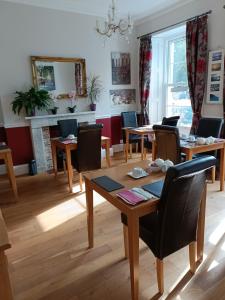 a dining room with tables and chairs and a fireplace at Lawnswood Guest House in Torquay