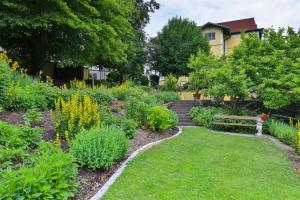 un jardín con un banco y muchas plantas en Kurhaus Dr. Petershofer en Wolfsegg am Hausruck