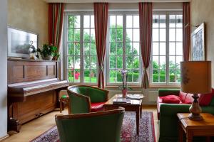 a living room with a piano and green chairs at Kurhaus Dr. Petershofer in Wolfsegg am Hausruck