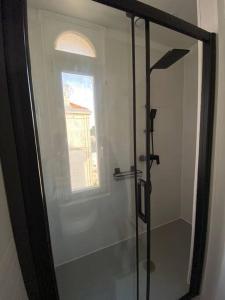 a glass shower in a bathroom with a window at Appartement, Royan. Proche plage. in Royan