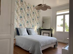 a bedroom with a white bed with a floral wallpaper at Appartement, Royan. Proche plage. in Royan