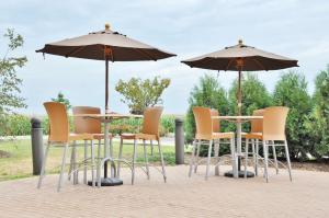 a group of chairs and tables with umbrellas at Hampton Inn Macomb in Macomb