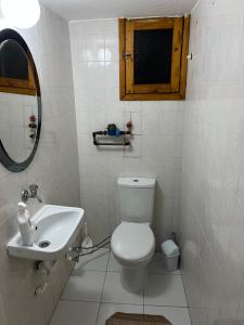 a white bathroom with a toilet and a sink at Lüks manzaralı daire in Burunabat