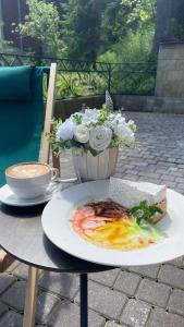 une table avec une assiette de nourriture et un bol de fleurs dans l'établissement Готель Вілла Драгобрат, à Dragobrat