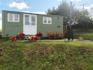 a green caravan with a table and chairs in a yard at The Journeyman Luxury Shepherds Hut in Barnoldswick