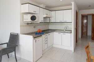 a kitchen with white cabinets and a sink and a microwave at Orly, A-6-38 PK 125 in Cullera