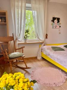 a bedroom with a bed and a chair and a window at Apartament Leszczyna in Olsztyn