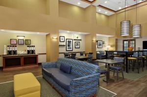 a waiting room with a couch and tables and chairs at Hampton Inn & Suites Madisonville in Madisonville