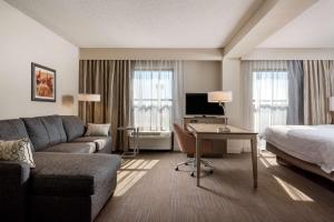 Habitación de hotel con sofá, cama y escritorio. en Hampton Inn Myrtle Beach West, en Myrtle Beach