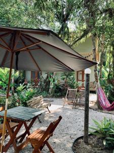 a patio with an umbrella and a table and chairs at Suites surf house itamambuca in Ubatuba