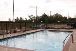 una piscina con sedie, tavoli e recinzione di Hampton Inn & Suites Natchez a Natchez