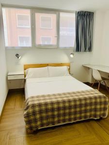 a bedroom with a bed and a desk and two windows at Apartamento full equip. in Bilbao