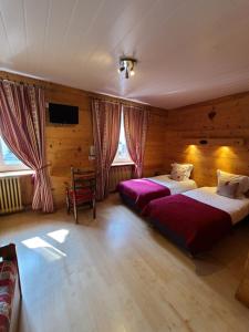 a bedroom with two beds and a tv in it at Hôtel du Centre in Valloire