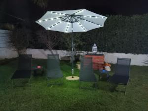 un groupe de chaises et un parasol dans l'herbe dans l'établissement Villa Anna B&B, à Syracuse