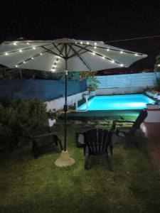 una sombrilla, una mesa y sillas junto a una piscina en Villa Anna B&B en Siracusa