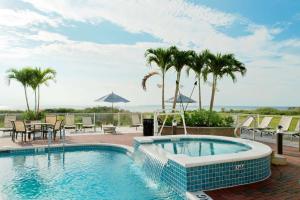 a swimming pool with tables and chairs and palm trees at Hampton Inn & Suites Ocean City Bayfront-Convention Center in Ocean City