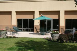 a patio with a blue umbrella in front of a building at Hampton Inn Olive Branch in Olive Branch