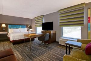 Habitación de hotel con cama y escritorio con TV. en Hampton Inn Olive Branch, en Olive Branch