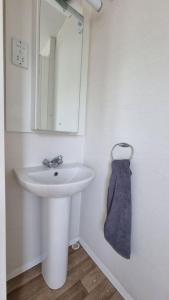 a white bathroom with a sink and a mirror at The Summer House in Heysham