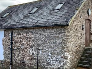 un bâtiment en pierre avec un toit avec une horloge. dans l'établissement The Granary Cottage, à Burrington