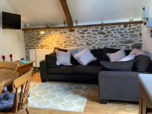 a living room with a couch and a stone wall at The Granary Cottage in Burrington