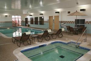 - une piscine avec des chaises, une table et un parasol dans l'établissement Newly Renovated Hampton Inn Omaha West Lakeside, à Omaha