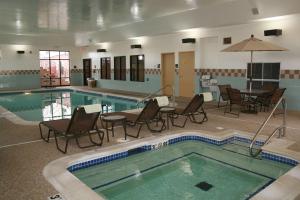 einen Pool mit Stühlen, einem Tisch und einem Sonnenschirm in der Unterkunft Newly Renovated Hampton Inn Omaha West Lakeside in Omaha