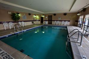 a large swimming pool with white chairs and tables at Hampton Inn by Hilton Napanee in Napanee