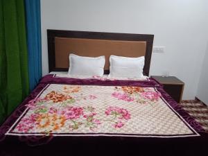 a bed with a quilt with flowers on it at Nubra Holiday in Deskit