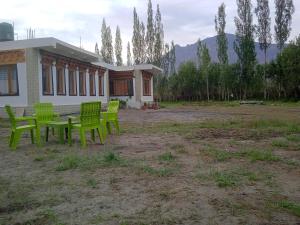 a group of green chairs sitting outside of a building at Nubra Holiday in Deskit
