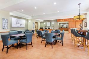 a restaurant with blue chairs and tables and a kitchen at Hampton Inn West Palm Beach-Lake Worth-Turnpike in Lake Worth