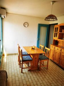 einen Holztisch und Stühle in einer Küche mit einer Uhr an der Wand in der Unterkunft Charmant T2 climatisée au coeur du village in Saint-Mandrier-sur-Mer