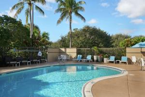 a swimming pool with chairs and palm trees at Hampton Inn Juno Beach in Juno Beach