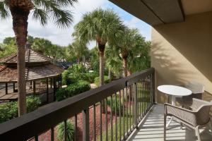 a balcony with a table and chairs and palm trees at Hampton Inn Juno Beach in Juno Beach